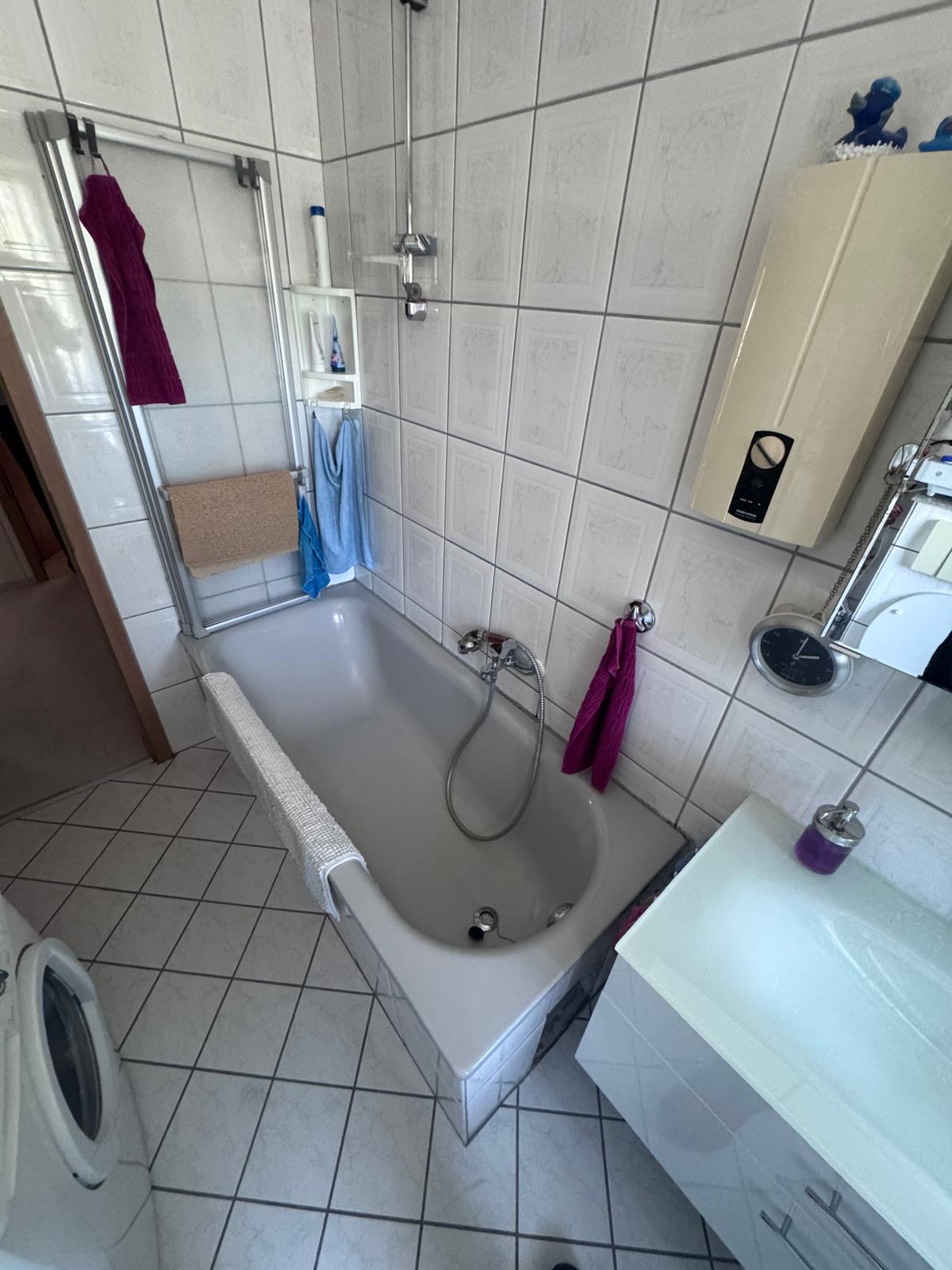 Bad vor Umbau: alte Badewanne mit Duschaufsatz, schmaler Einstieg